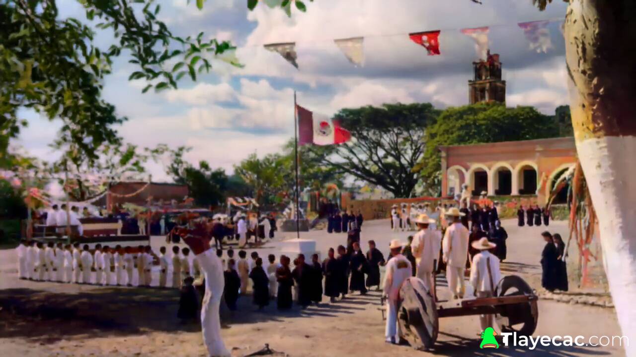 Niños y adultos se reúnen en una plaza. Una bandera de México en el centro. Una iglesia y un edificio al fondo.